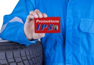 Closeup of male mechanic with blue uniform standing near tires and showing a gift card